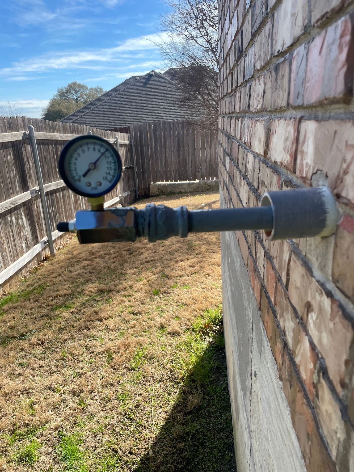 A pressure gauge is attached to a brick wall