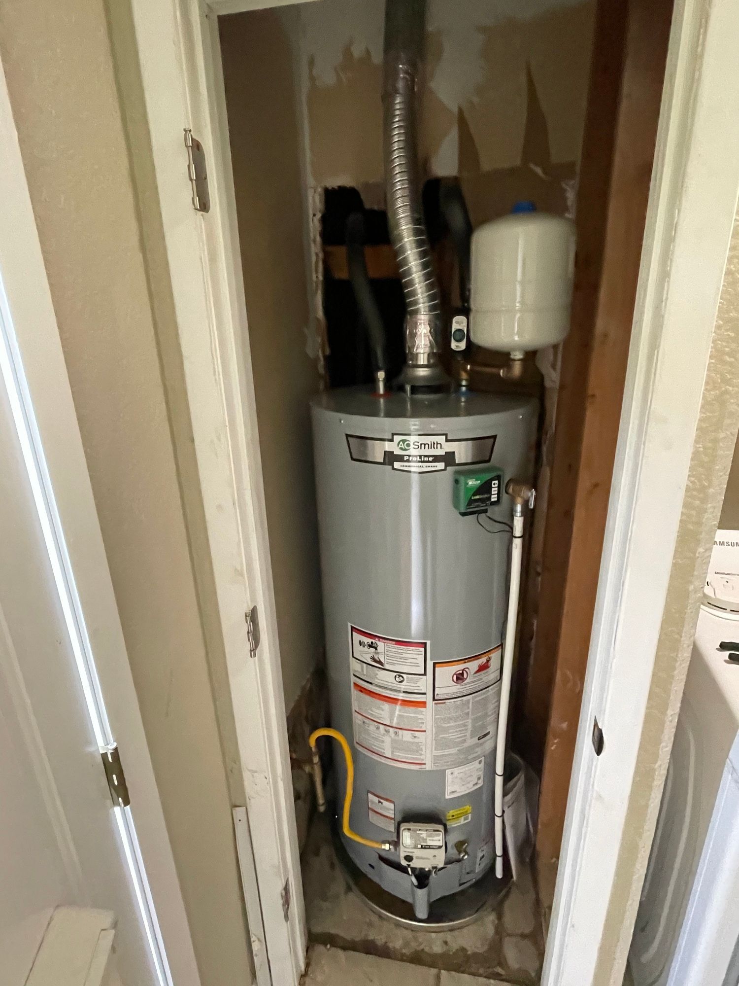 A water heater is sitting in a closet next to a door