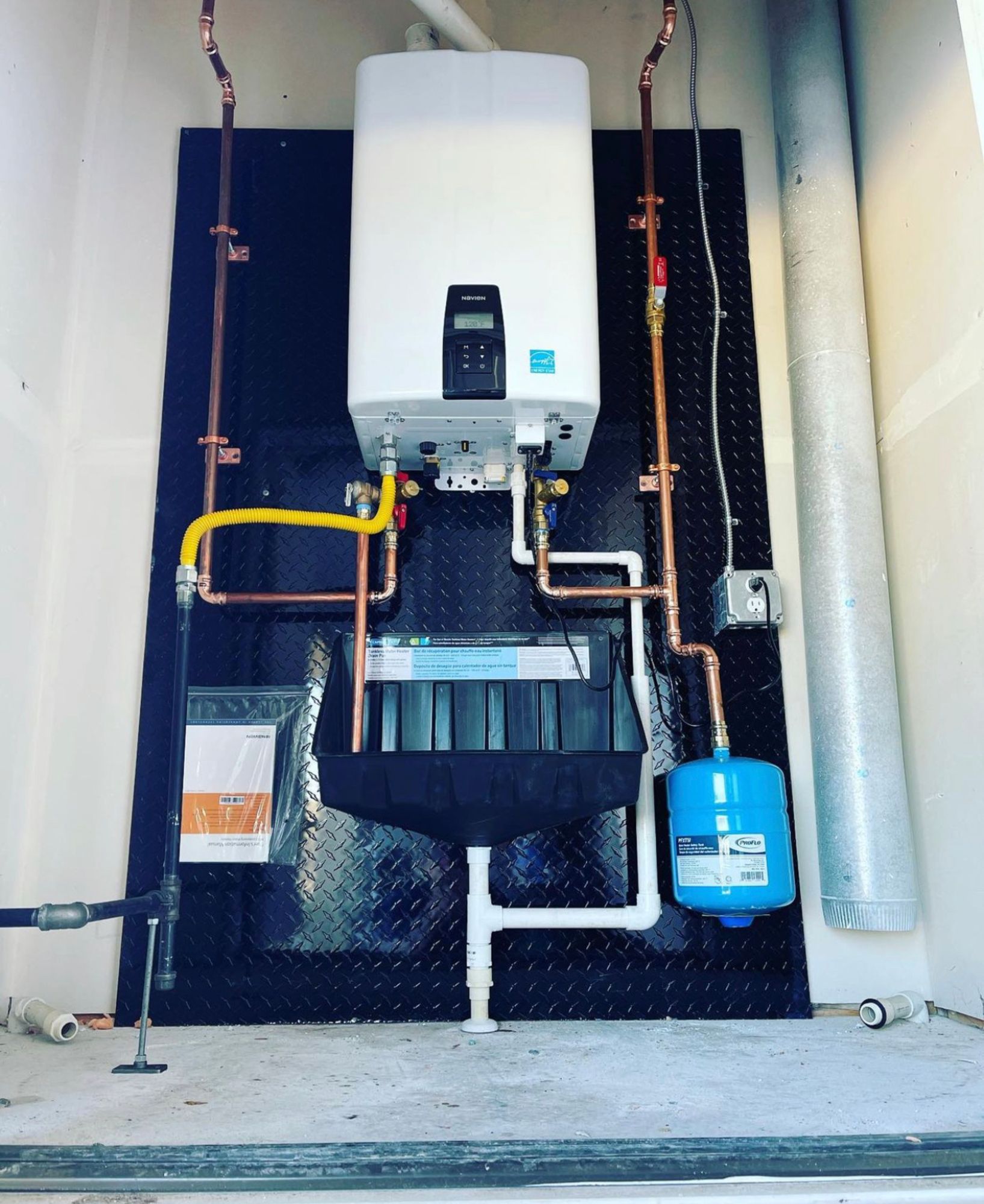 A water heater is mounted to a wall with copper pipes