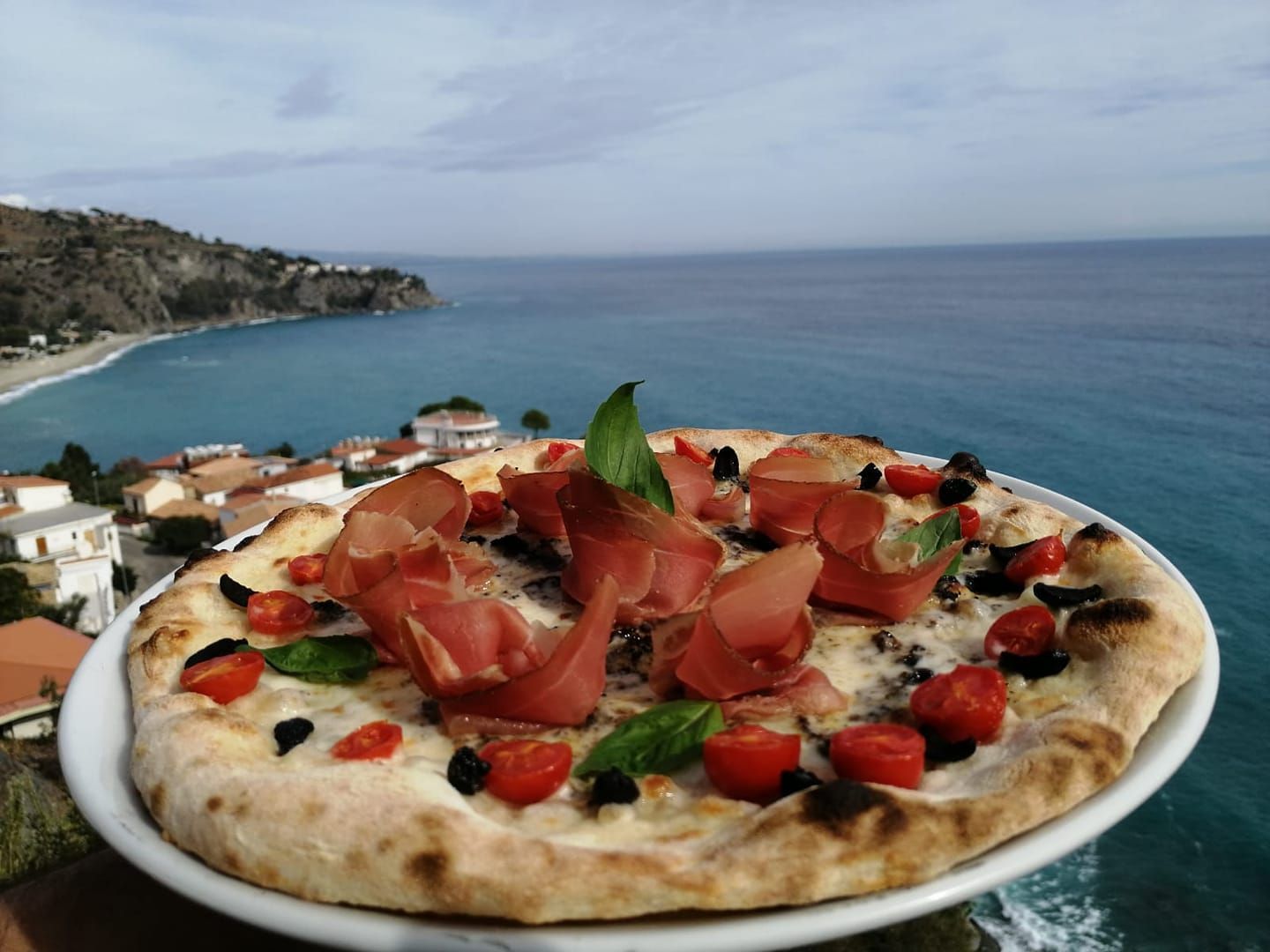 Una pizza su un piatto con l'oceano sullo sfondo