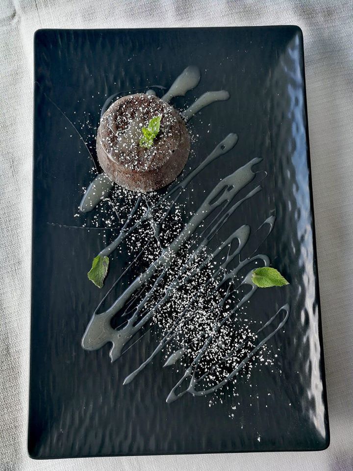 Un piatto nero con un dolce al cioccolato sopra