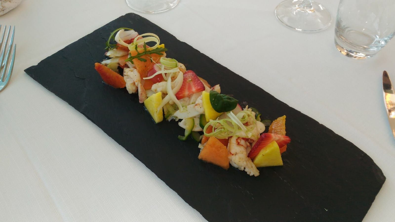 Un piatto nero con un'insalata sopra su un tavolo