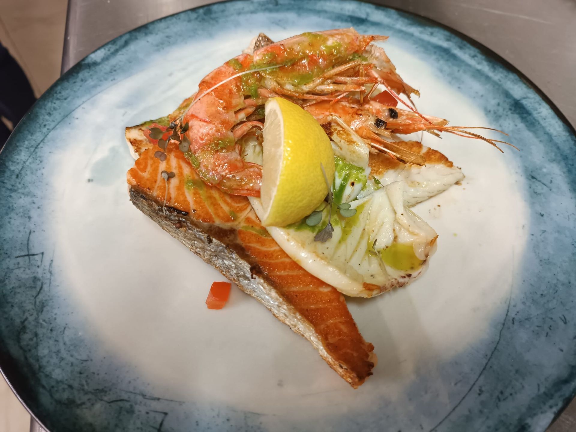 Un primo piano di un piatto di cibo con gamberi e salmone su un tavolo.