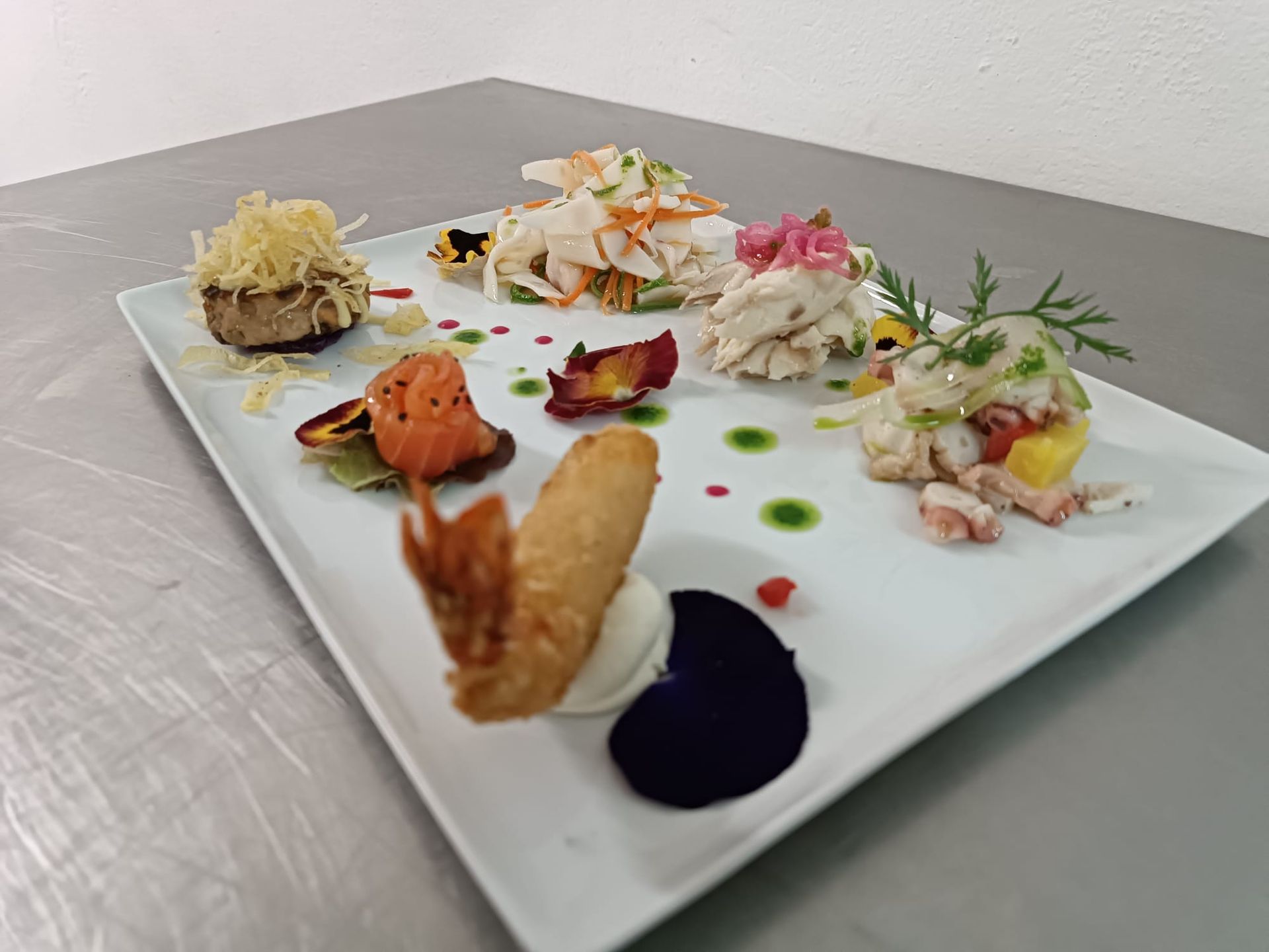 Un piatto bianco sormontato da una varietà di cibo su un tavolo.