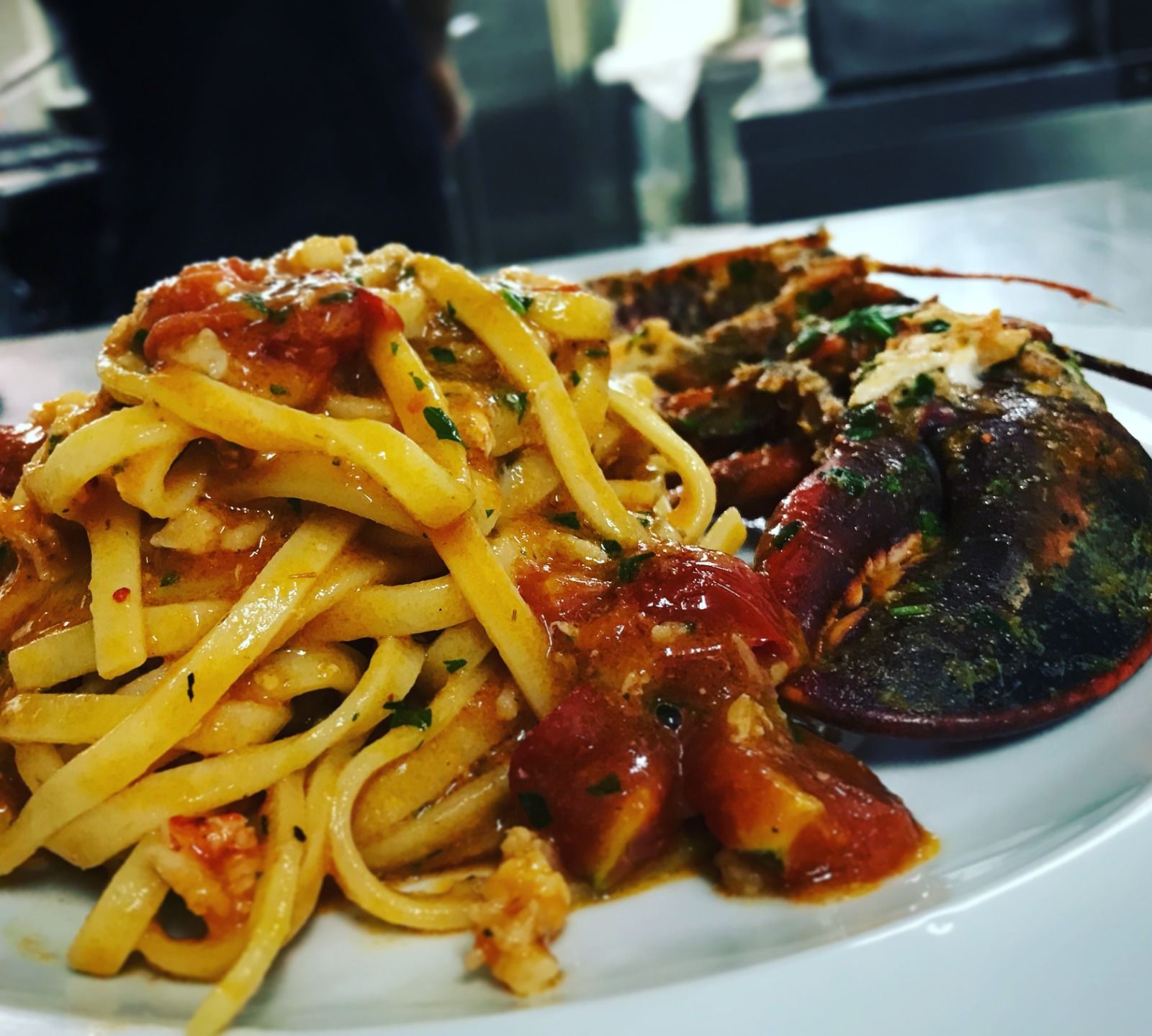 Un piatto bianco con sopra delle tagliatelle e un'aragosta