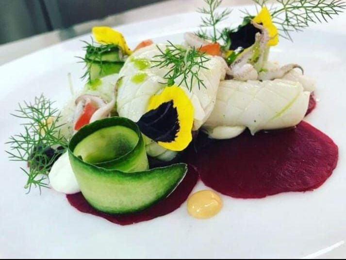 Un piatto bianco condito con una varietà di verdure e salse