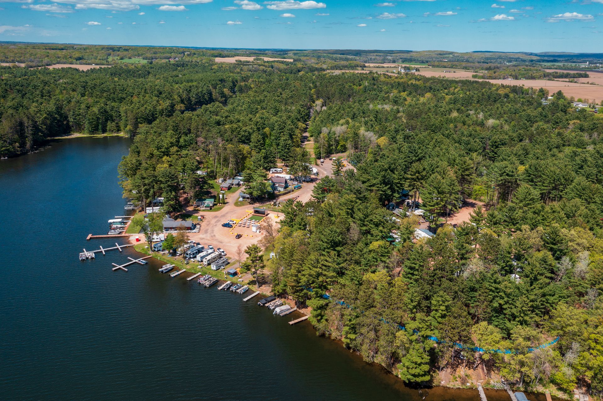 Aerial view of a lakeside forest resort with docks, boats, and cabins along the shoreline