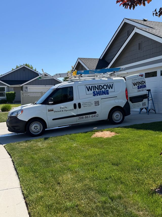 White Windows Shine van parked in a suburban driveway beside a gray house on a sunny day