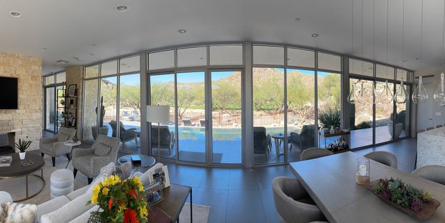 Modern living room with floor-to-ceiling glass doors overlooking a pool and mountain view