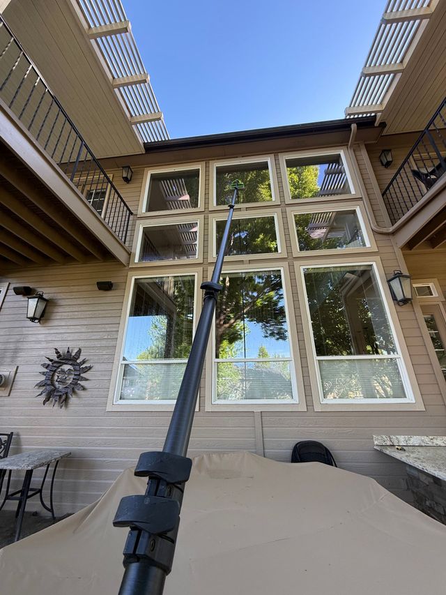 Courtyard patio with a large window wall, pergola overhead, and a selfie stick in the foreground