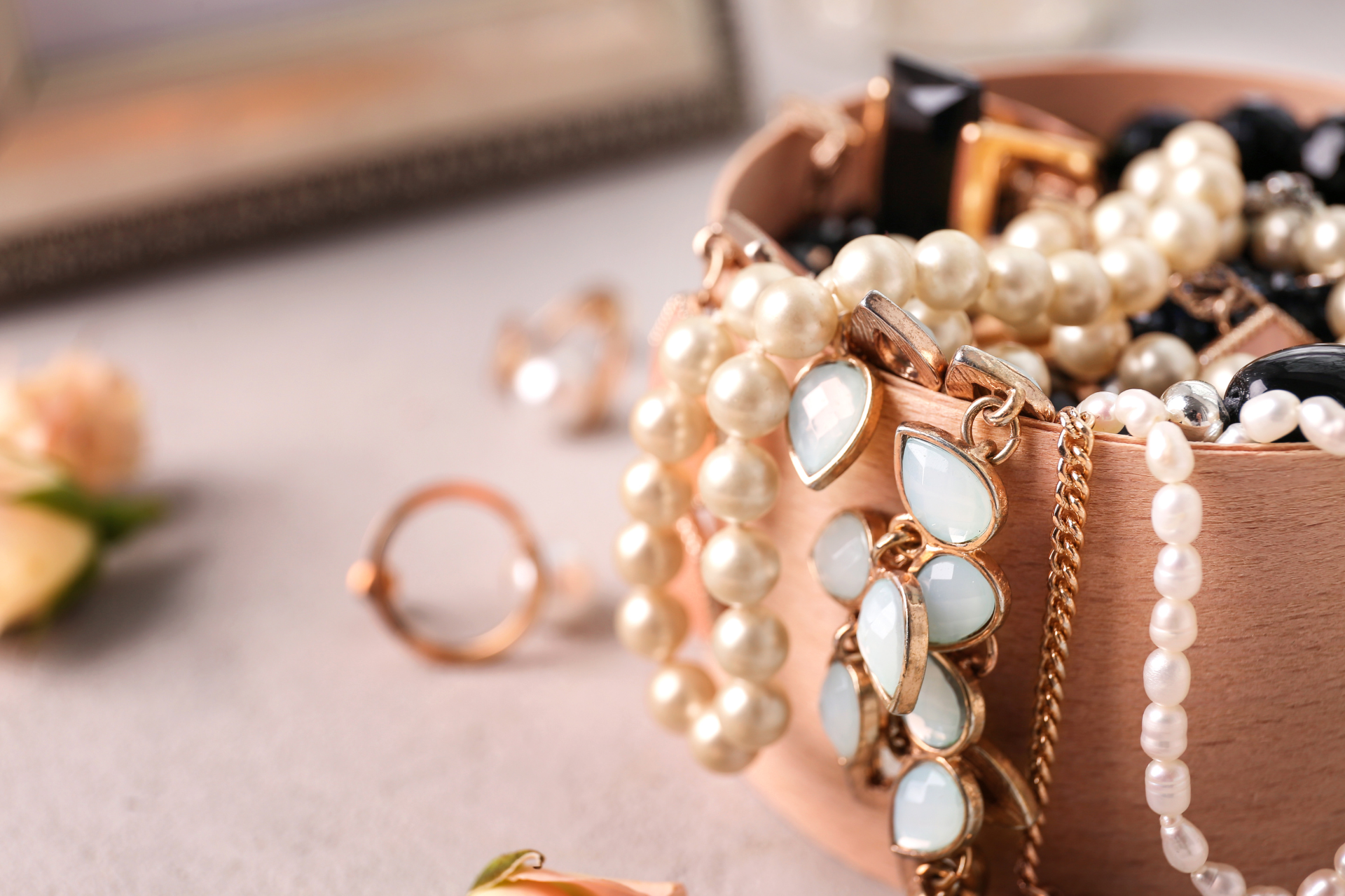 Pearl necklace and jeweled jewelry box on a soft beige surface