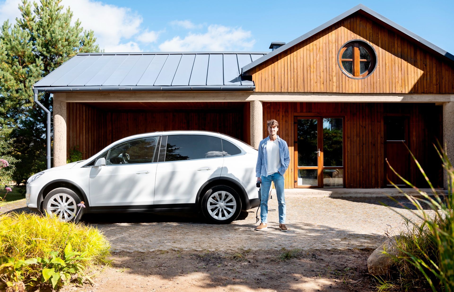 White SUV parked in front of a wooden house, with a person standing by the front entrance.