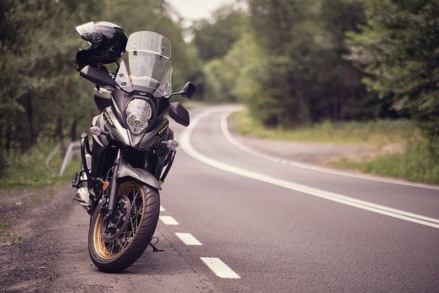 Motorcycle parked on a winding road with a forest backdrop