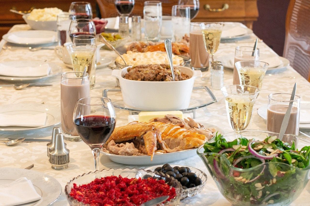 Set dining table with bread, salad, berries, wine glasses, and serving dishes ready for a meal