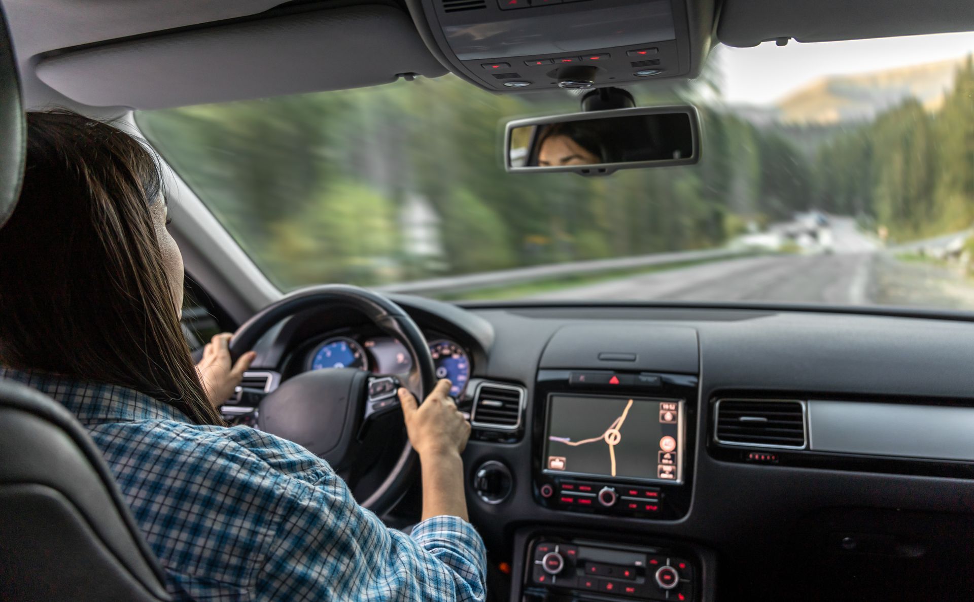 Driver steering a car on a highway, GPS map visible on the center console