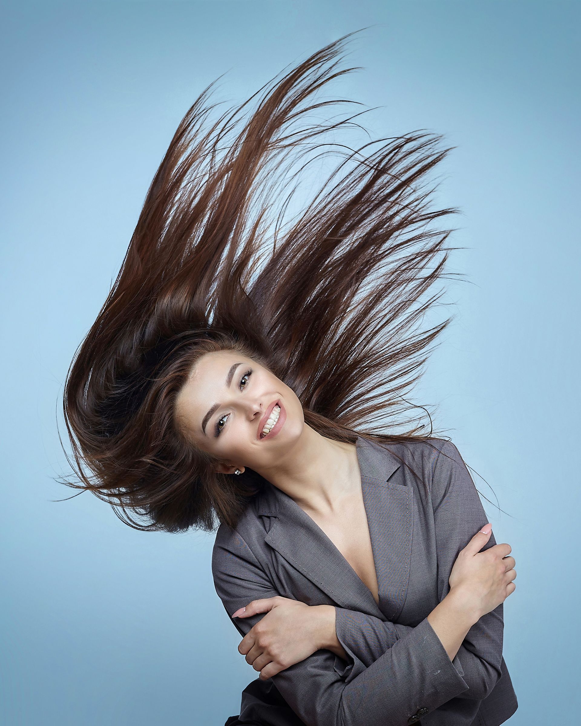 A woman in a suit with her hair blowing in the wind.