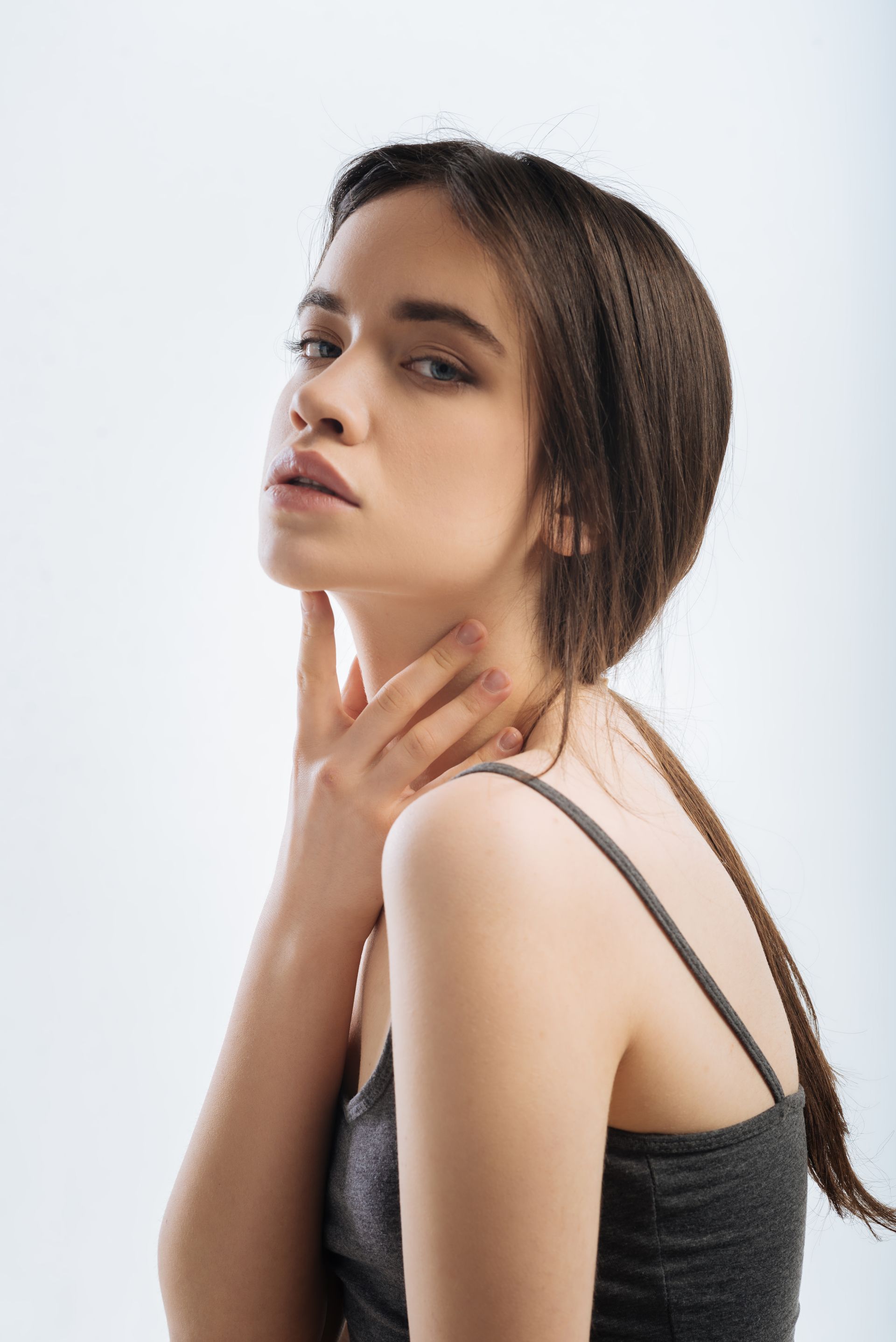 woman touching her neck while gazing camera turning face camera