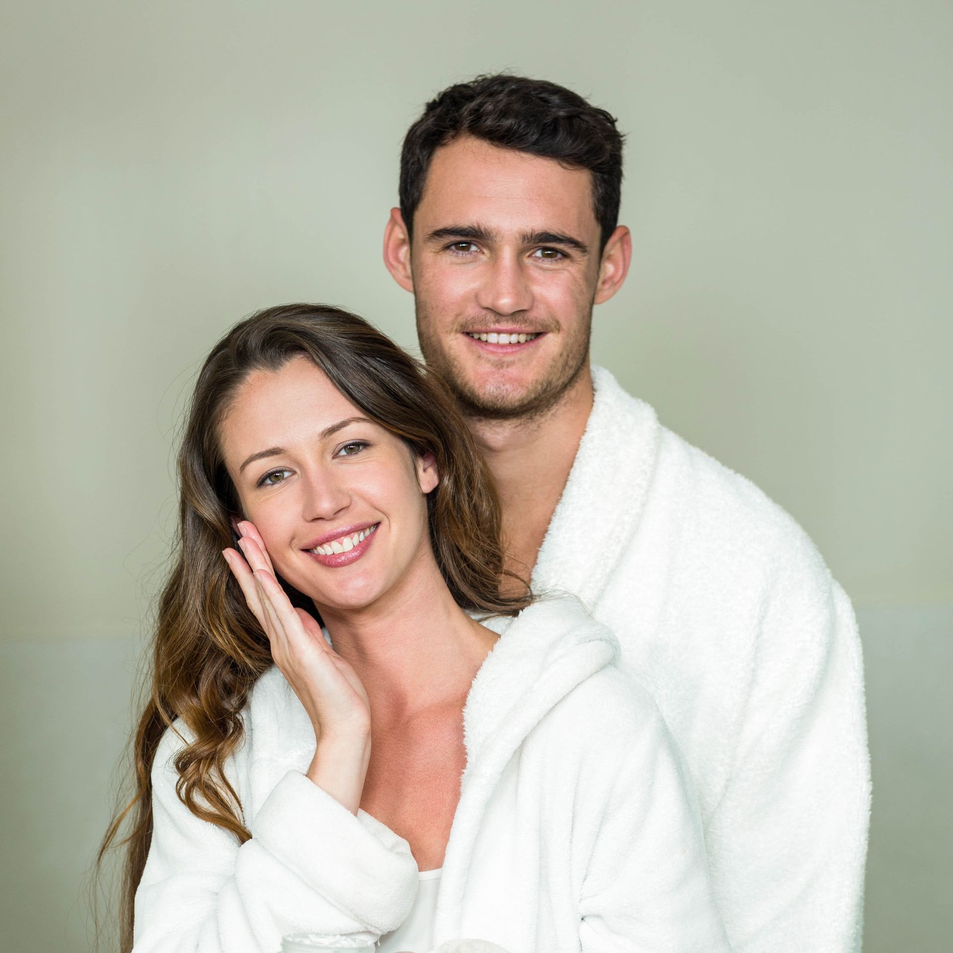 A man and a woman in bathrobes are standing next to each other in a bathroom.