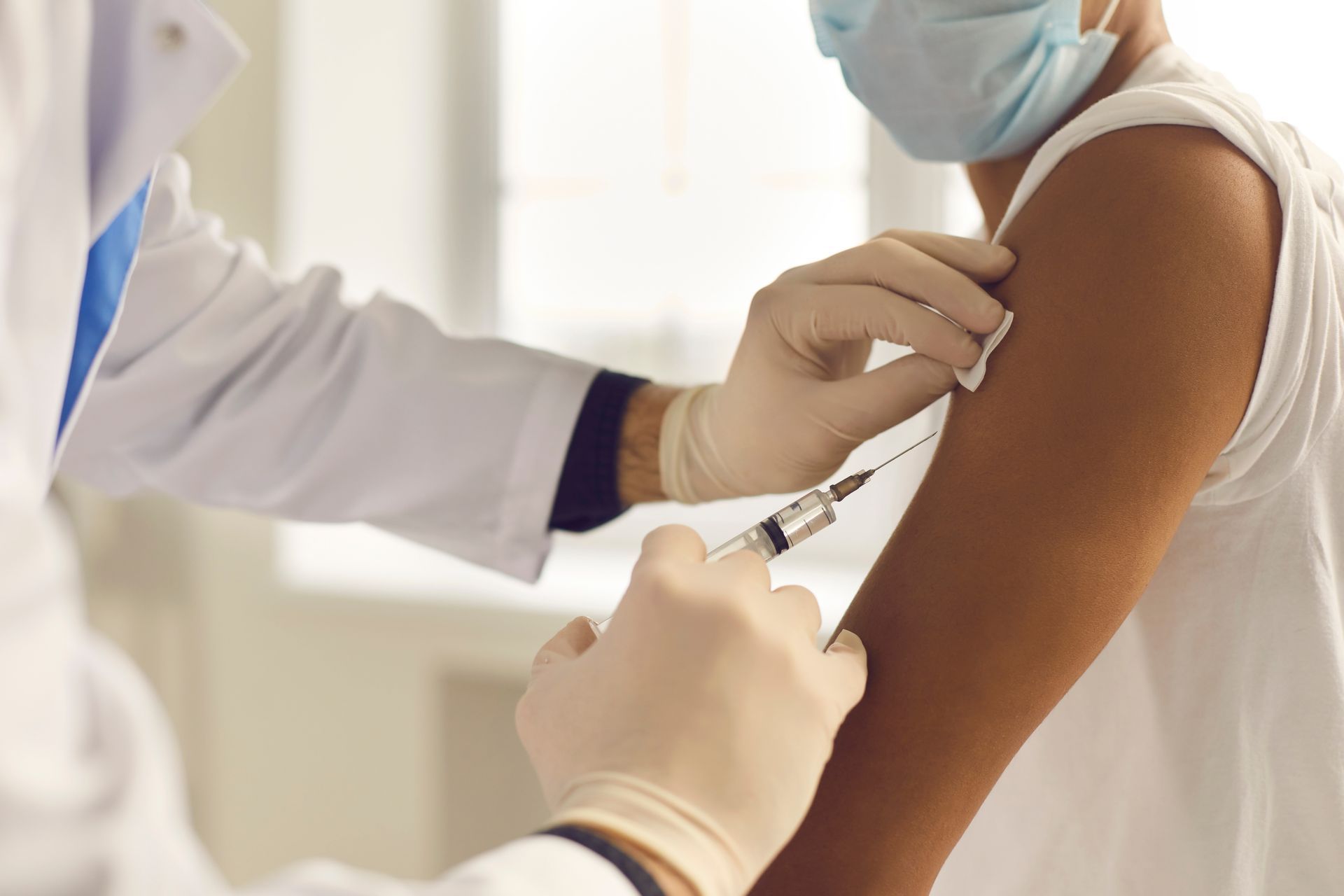 A doctor is giving a vaccine to a patient who is wearing a mask.