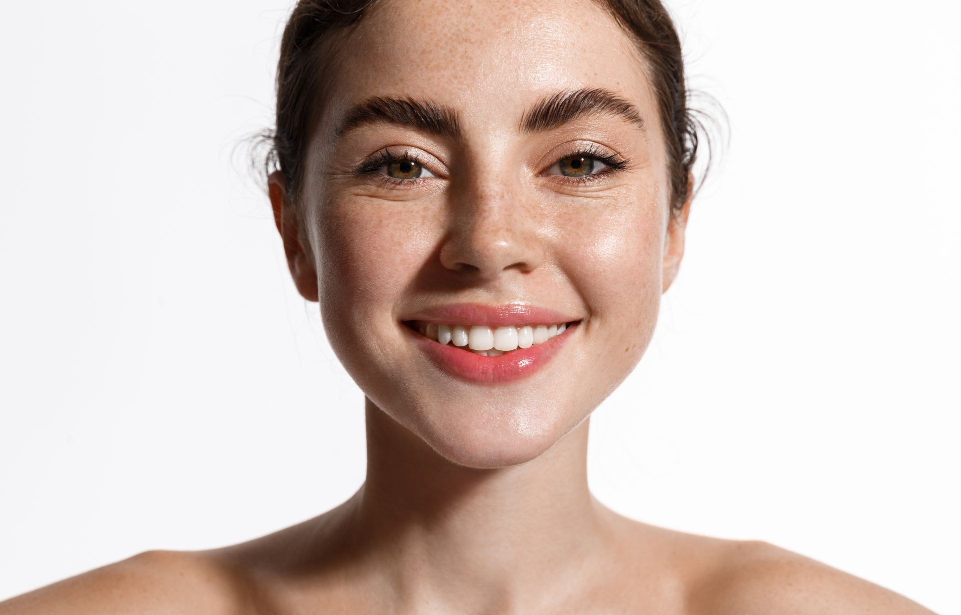 Woman with freckles and a wide smile against a white background.