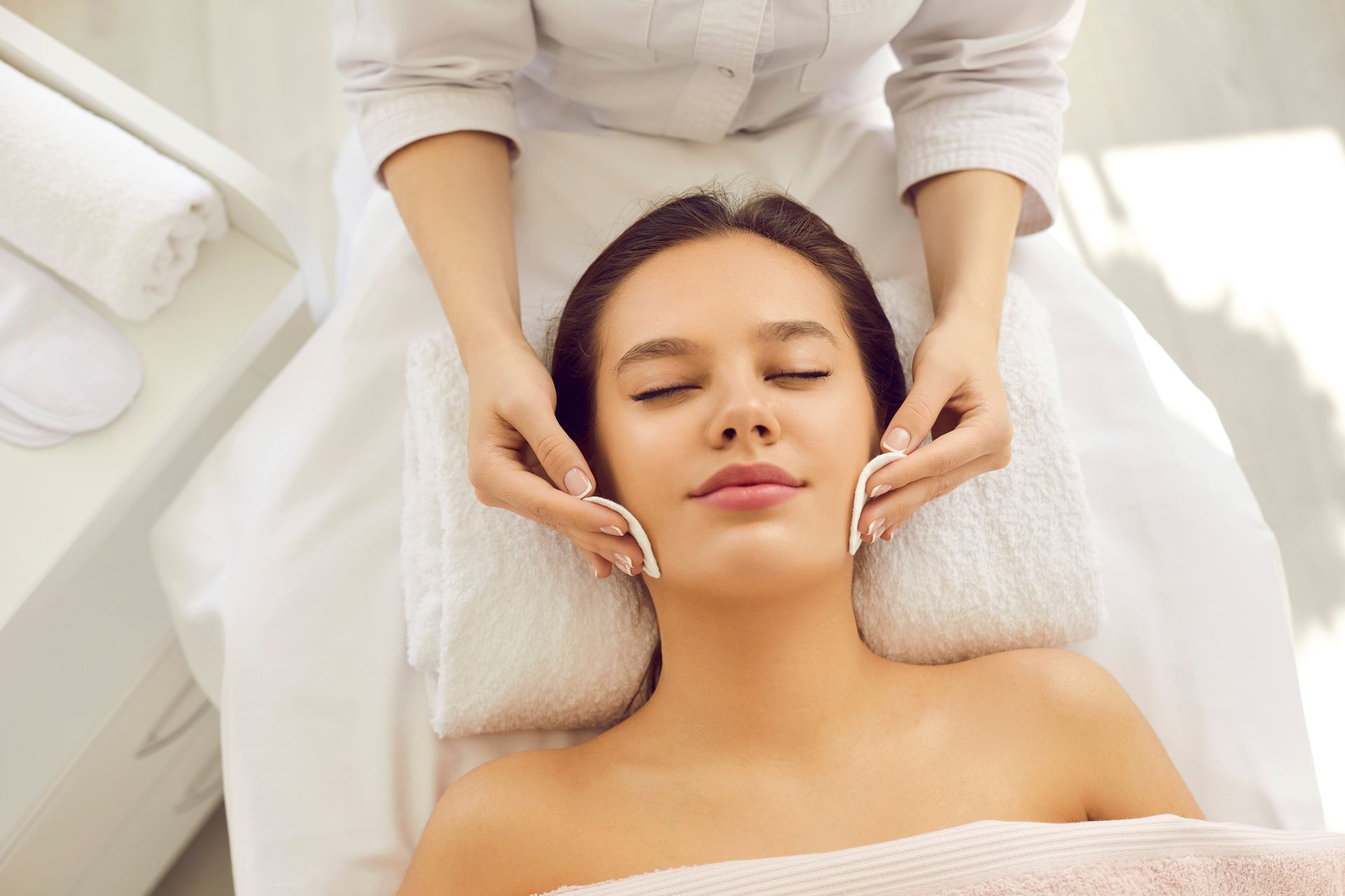 Spa therapist giving a facial massage to a relaxed client on a treatment bed