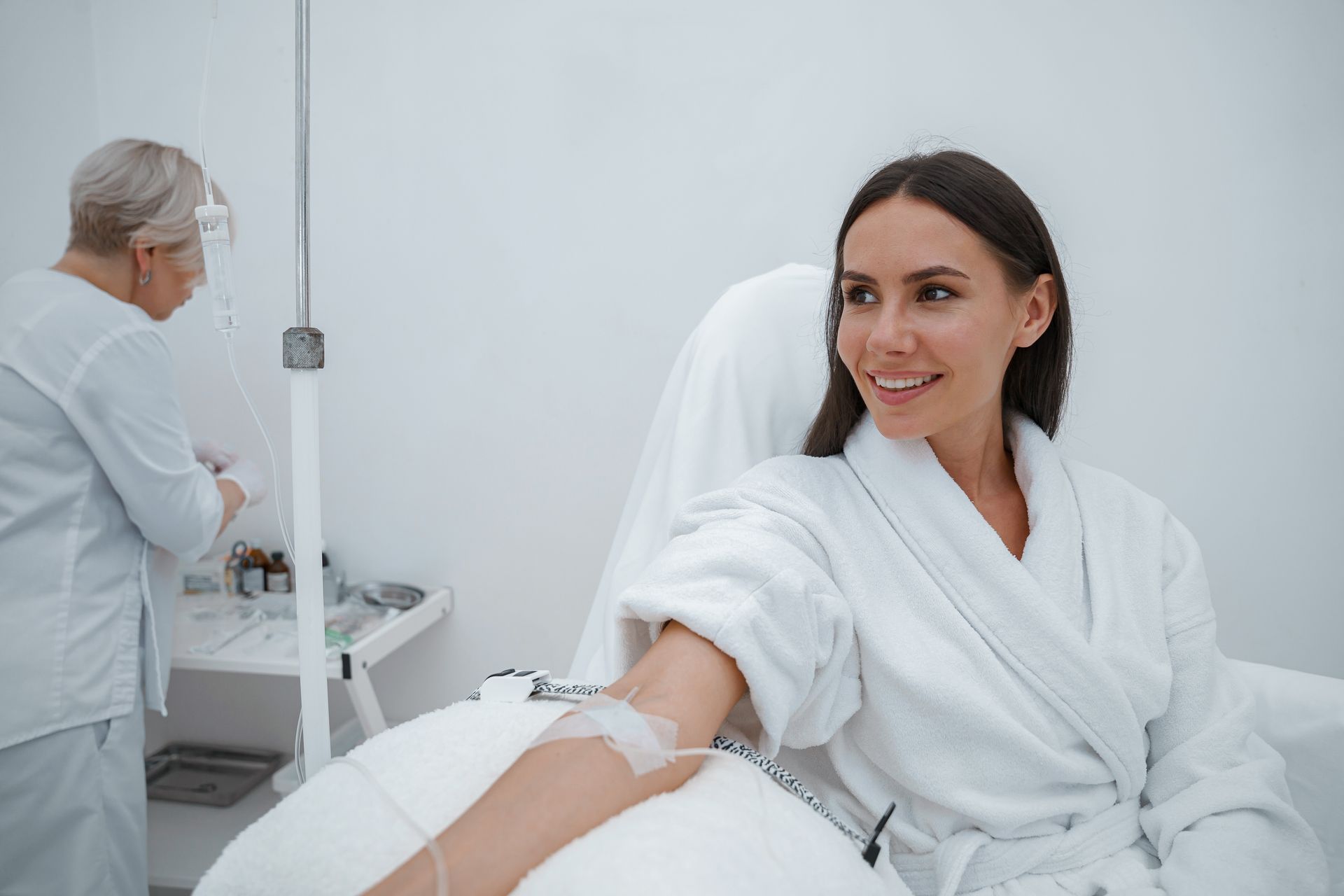 A woman is sitting in a hospital bed with an iv in her arm.