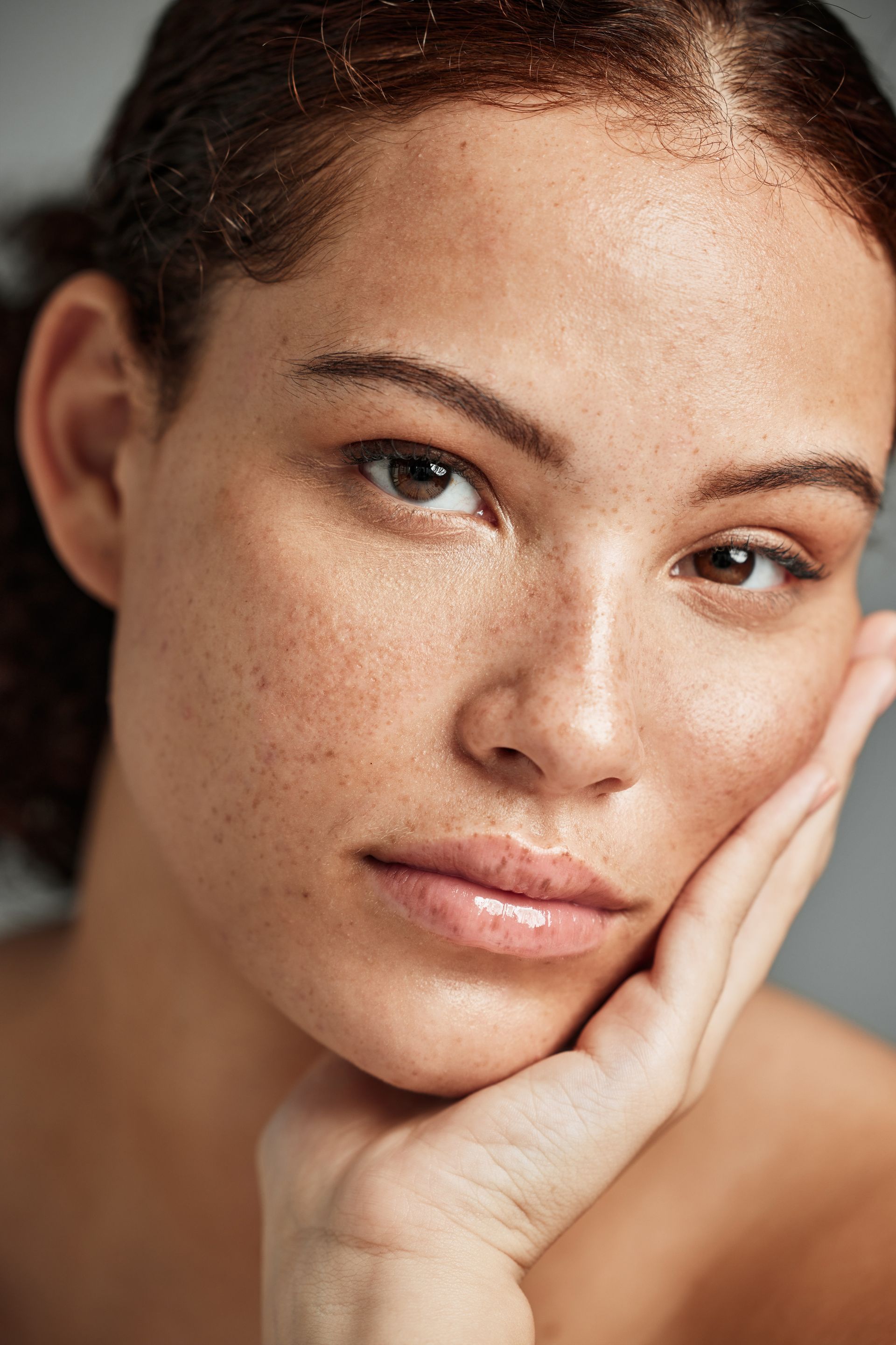 A close up of a woman 's face with her hand on her chin.