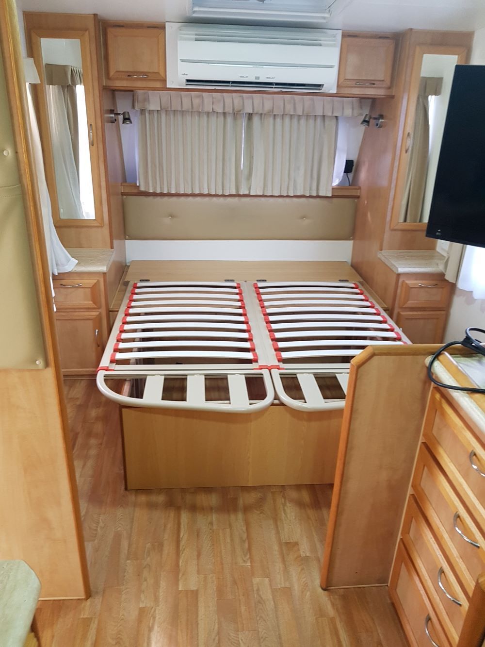 A Bedroom in a Camper With a Bed and a Television — Dempsters Caravan & RV in Thabeban, QLD