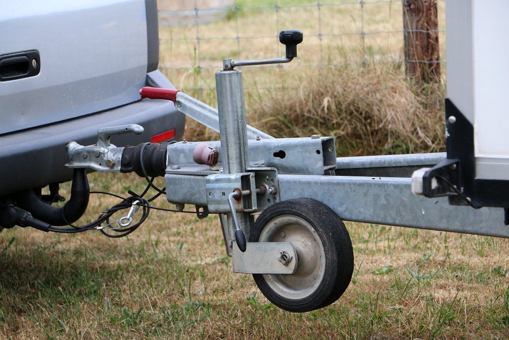 A Trailer is Attached to a Car in a Field — Dempsters Caravan & RV in Bundaberg, QLD