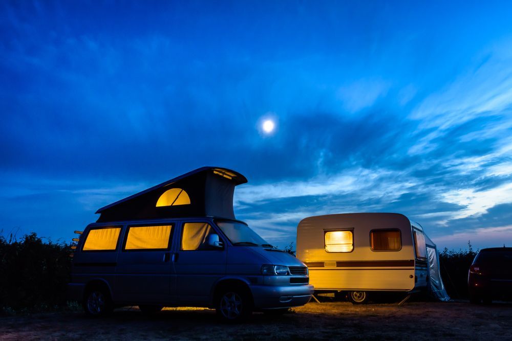 Two Camper Vans Parked at Dusk Under a Bright Blue Sky — Dempsters Caravan & RV in Childers, QLD