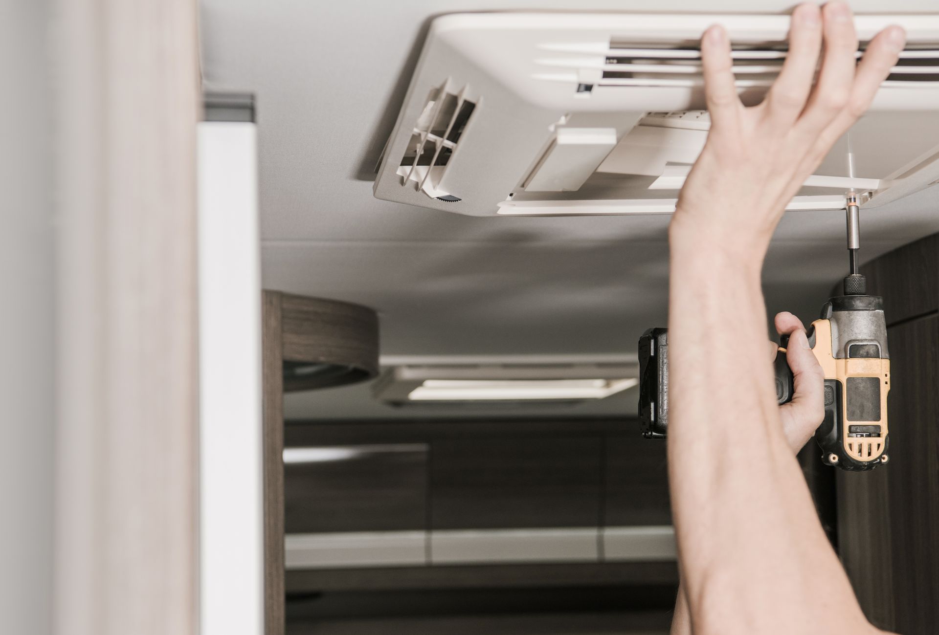 Person Adjusting a White Cabinet Light Fixture — Dempsters Caravan & RV in Gin Gin, QLD