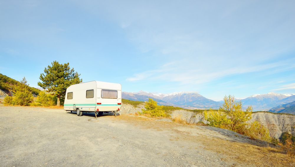 White Rv Parked on a Gravel Overlook With Mountains — Dempsters Caravan & RV in Childers, QLD