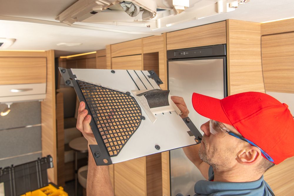 MAN in Red Cap Inspecting a Vent Filter Inside a Wood-paneled Rv Ceiling — Dempsters Caravan & RV in Gin Gin, QLD