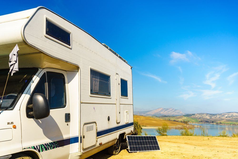 A White Rv is Parked in a Field Next to a Lake — Dempsters Caravan & RV in Hervey Bay, QLD