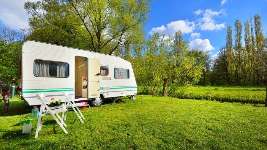 A Camper Trailer is Parked in a Grassy Field — Dempsters Caravan & RV in Gladstone, QLD