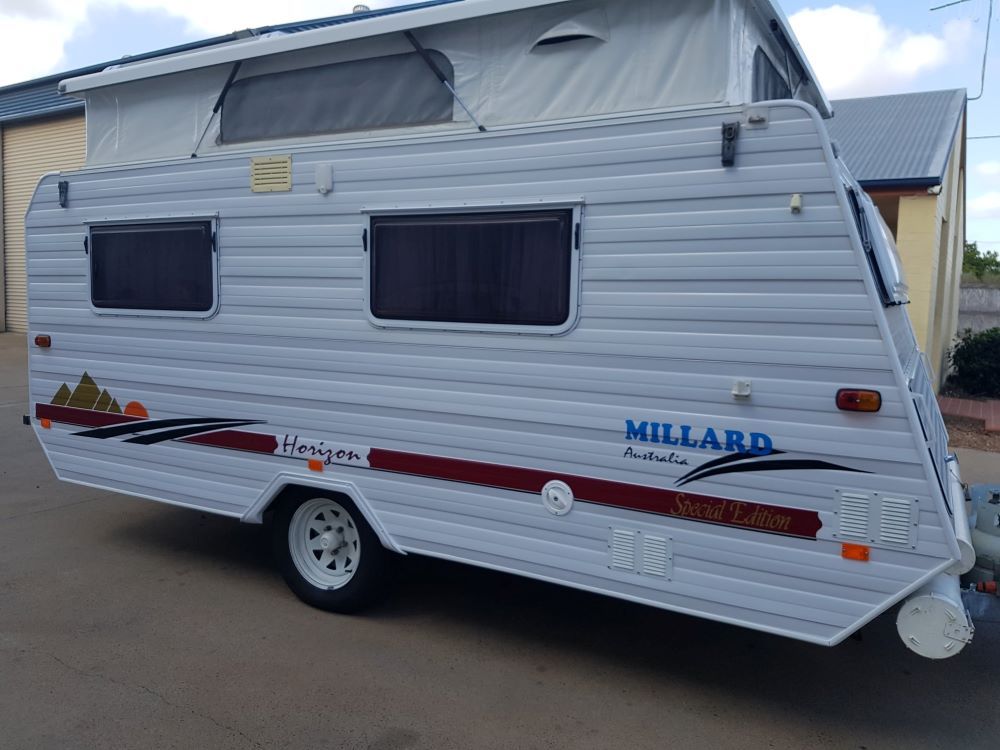 A White Trailer With a Pop Top Roof is Parked in Front of a Building — Dempsters Caravan & RV in Thabeban, QLD