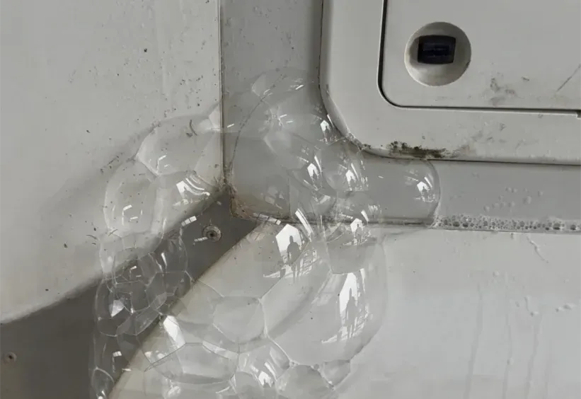 Clear packing tape sealing a white corner seam beside a panel on a wall.