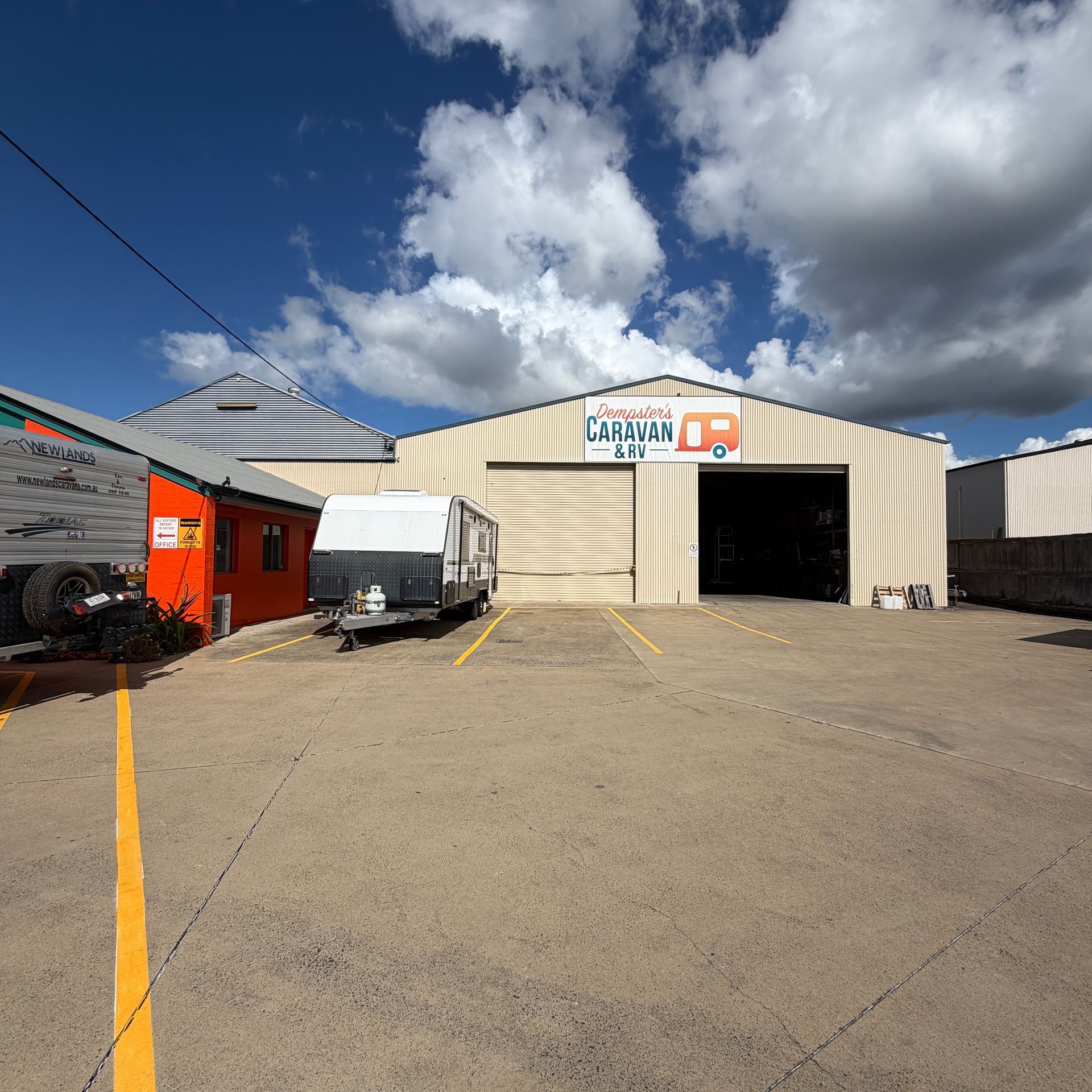 Industrial Warehouse Yard With White Truck, Red Building — Dempsters Caravan & RV in Gin Gin, QLD