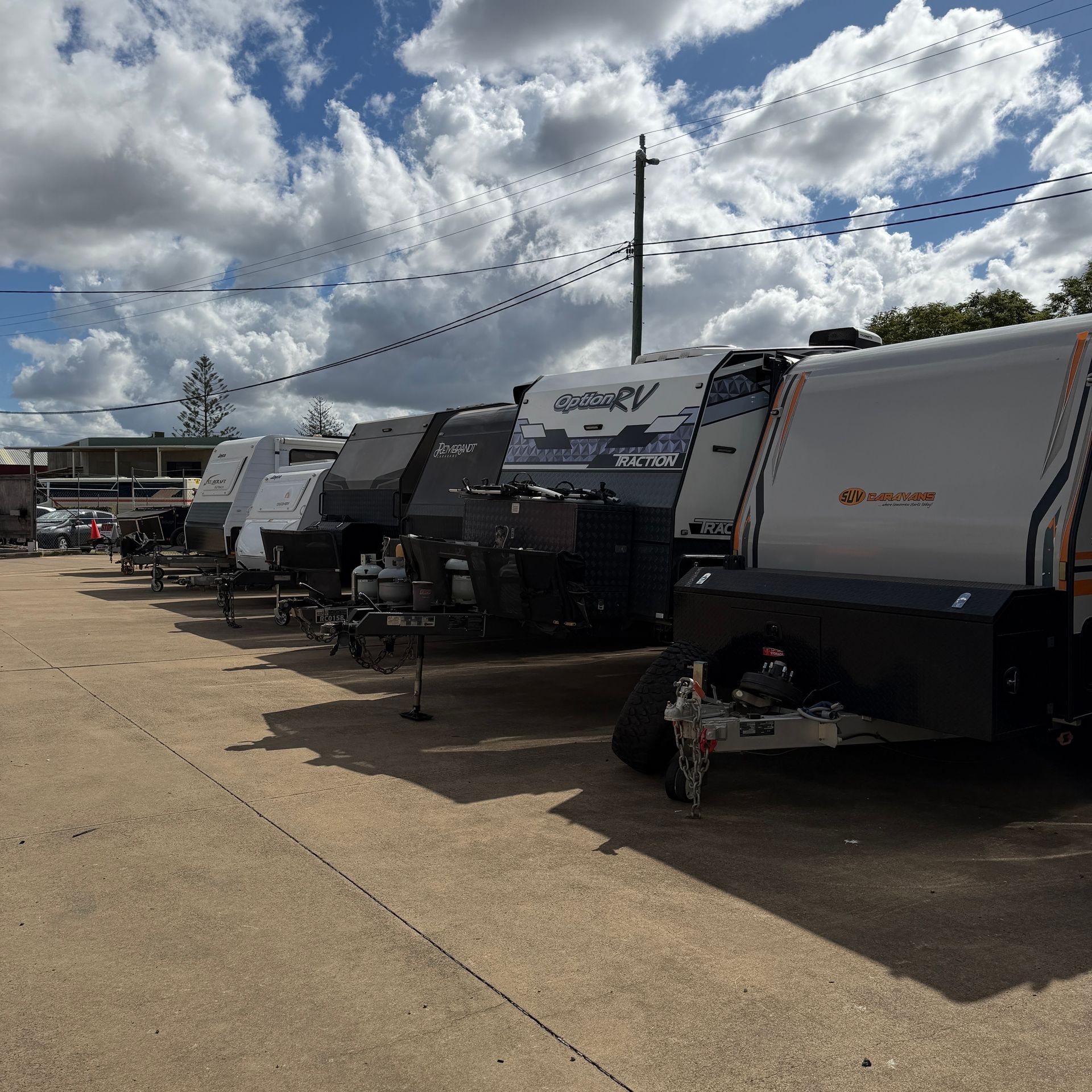 Row of Parked Rv Campers in a Lot Under a Cloudy Sky — Dempsters Caravan & RV in Childers, QLD