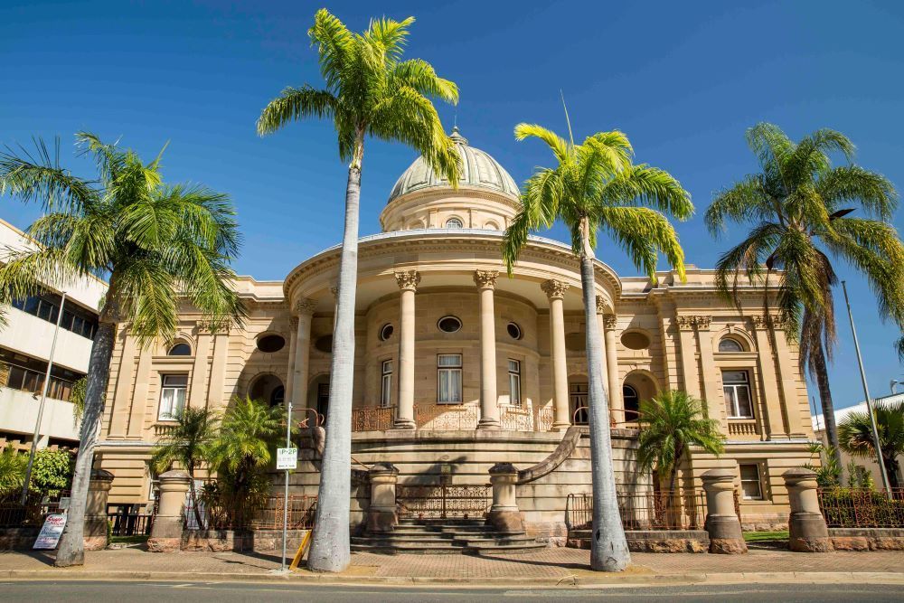 A Large Building With Palm Trees in Front of It — Dempsters Caravan & RV in Rockhampton, QLD
