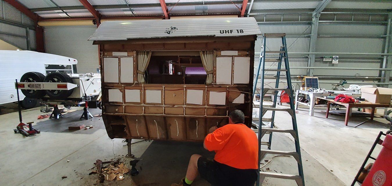 A Man is Working on a Trailer in a Garage — Dempsters Caravan & RV in Gladstone, QLD