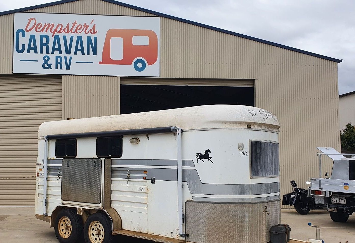 A Caravan is Parked in Front of a Building — Dempsters Caravan & RV in Thabeban, QLD