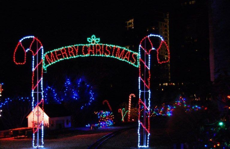 A nighttime Christmas display featuring a lighted archway with candy cane pillars and
