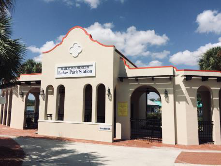 The historic Lakeside Park Station building in Tavares, Florida. A light-colored stucco building with arched openings and red trim under a bright blue sky.
