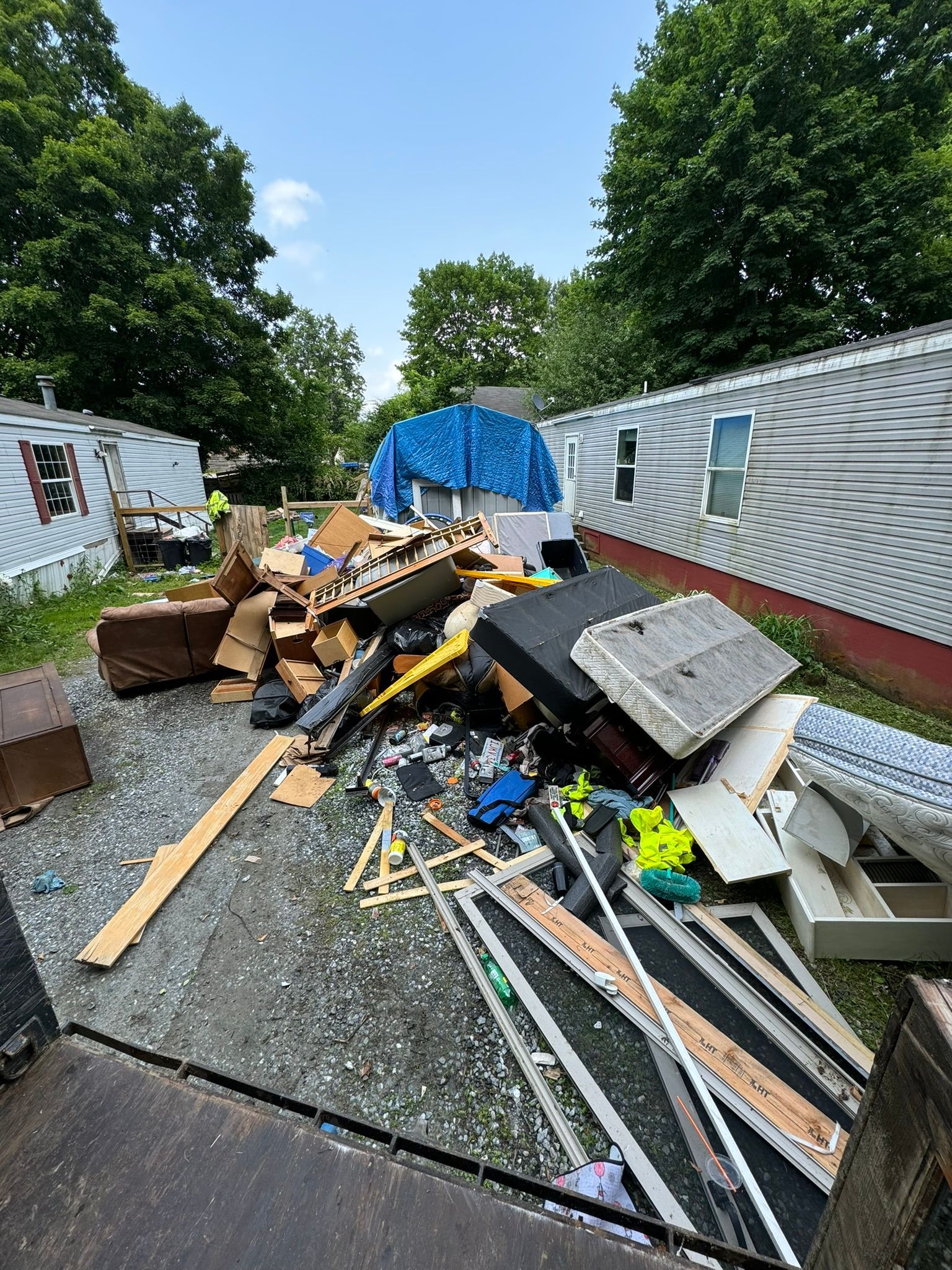 An unfinished attic space cluttered with loose debris, cardboard boxes, and piles of discarded materials.