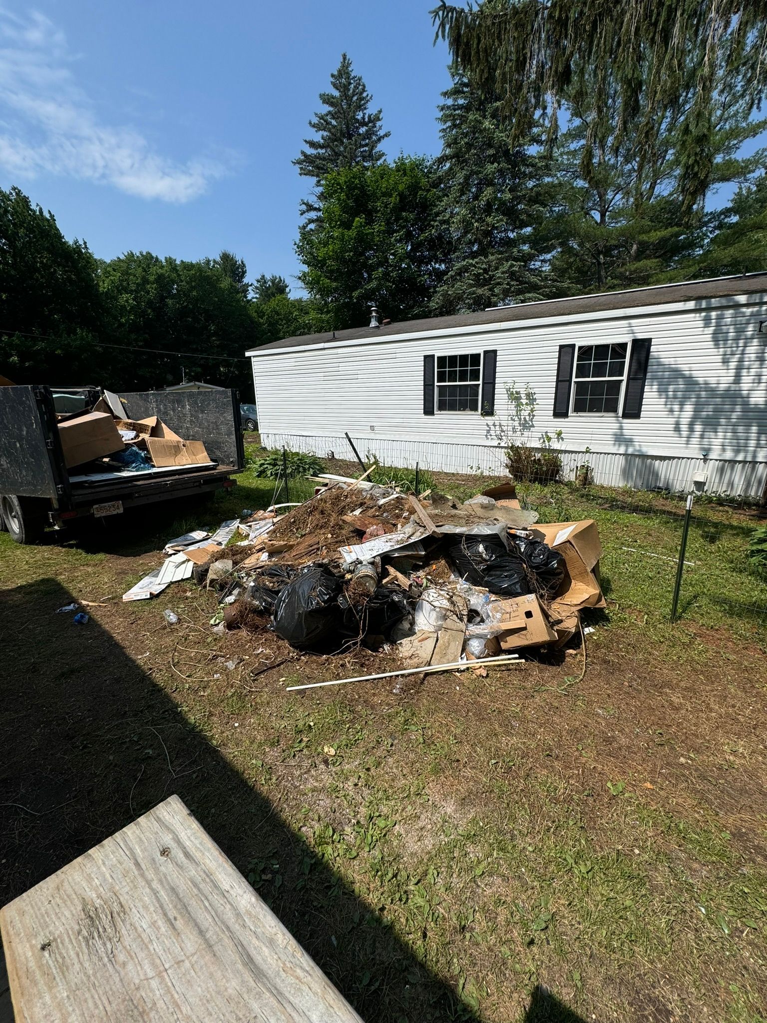 A cluttered attic space with exposed wooden roof rafters, filled with scattered cardboard boxes and debris.