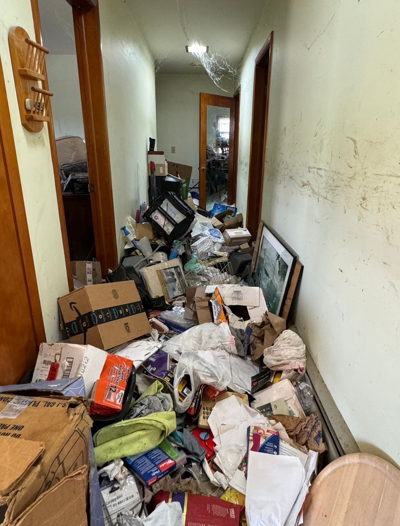 An unfinished attic space cluttered with loose debris, cardboard boxes, and piles of discarded materials.