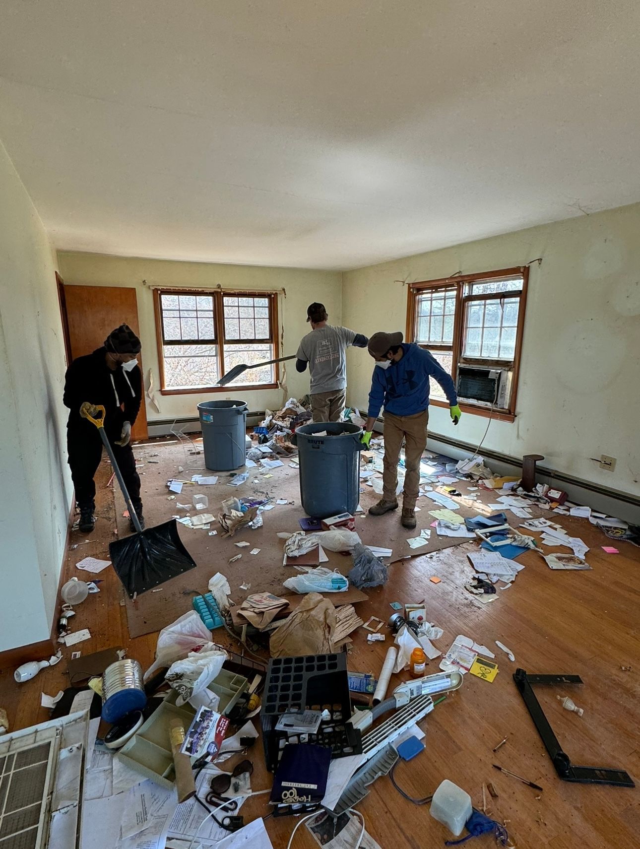 A cluttered attic space with exposed wooden roof rafters, filled with scattered cardboard boxes and debris.