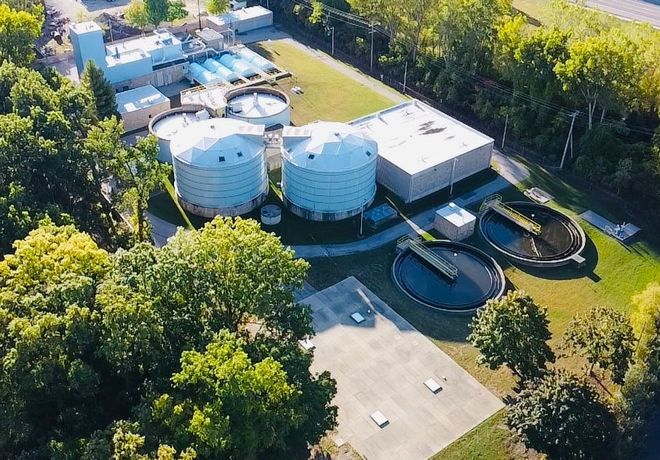 Aerial view of SWMUA water treatment facility with large circular tanks, buildings, and trees.
