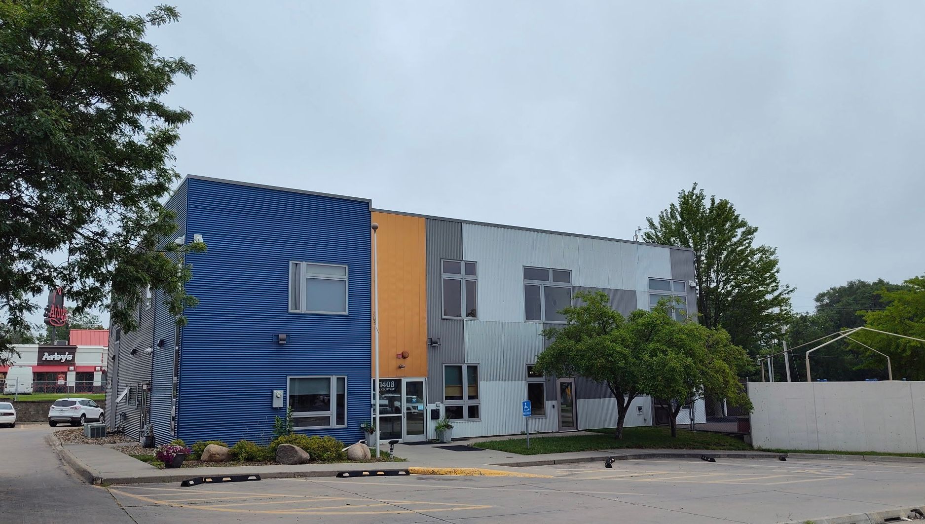 A two-story commercial building with a blue spiral-patterned corner, yellow accent, and a gray-paneled facade.